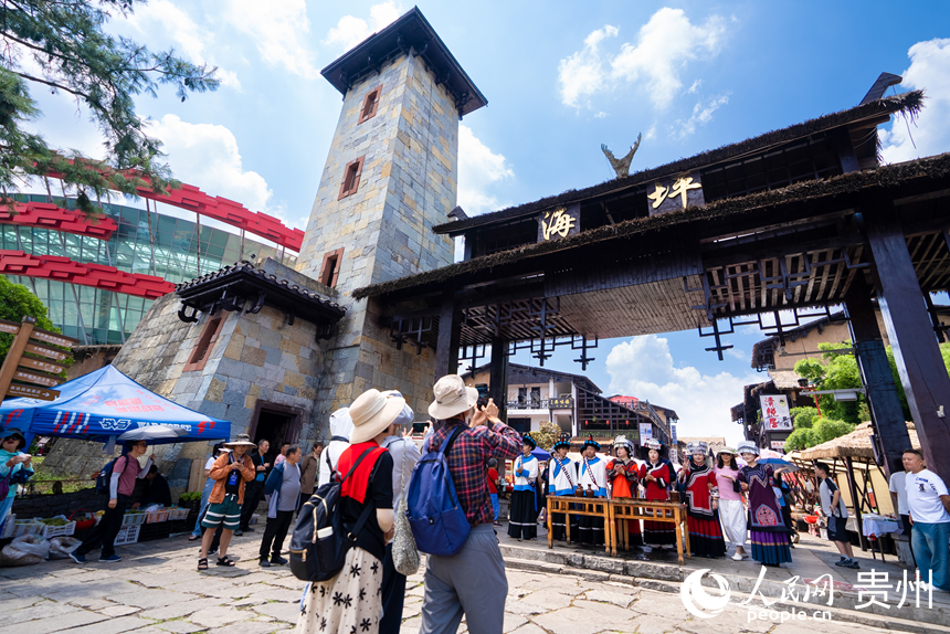 游客参观体验度假区内的彝族拦门酒。人民网记者 涂敏摄